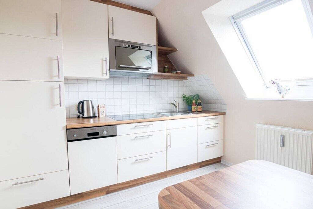 Eine moderne Küche mit weißen Schränken, einem eingebauten Backofen und einem Oberlicht.