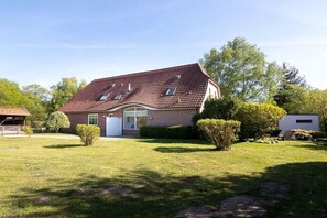 Een huis met twee verdiepingen, een schuin dak, een voortuin en een verzorgd gazon.