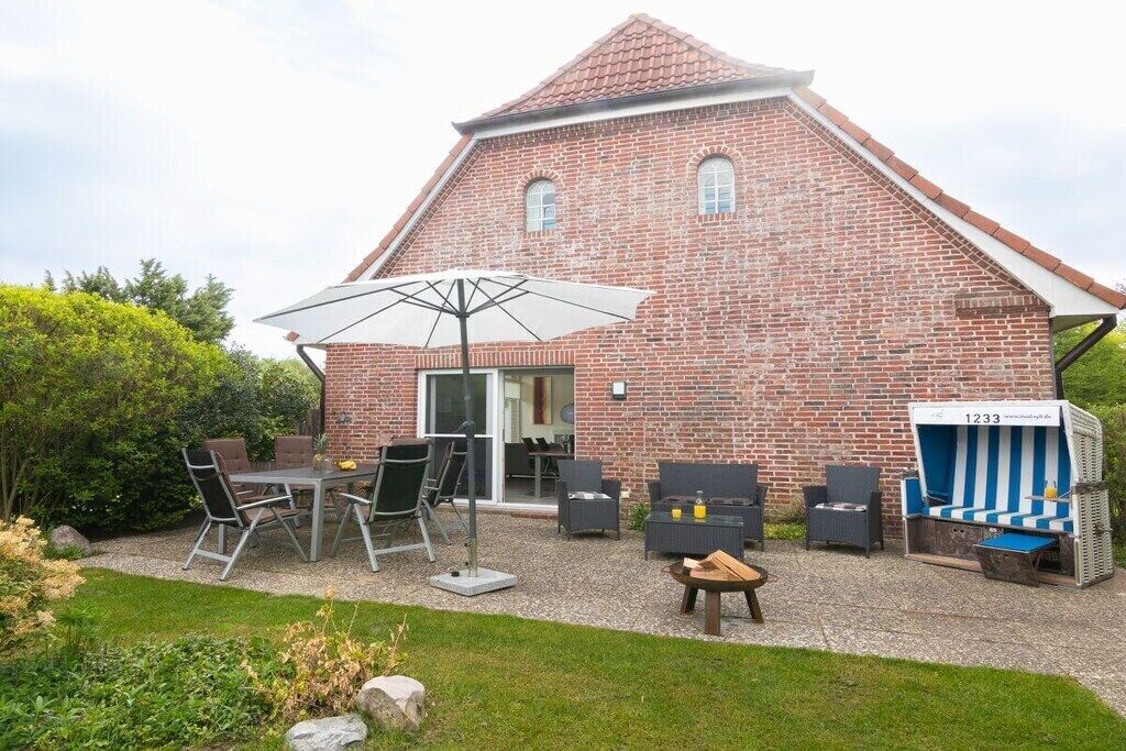 A brick building with a sloped roof, outdoor seating area with tables and chairs, and a blue-striped lounge chair.