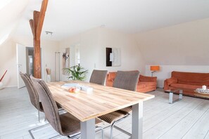 Een moderne woonruimte met een houten eettafel, zachte stoelen, een bank en een glazen salontafel.