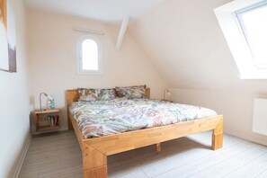 A bedroom with a sloped ceiling, a single bed, a small bedside table with a lamp, and a window. - Holiday home semi-detached house Braderup (Dagebüll OT Süderwaygaard)