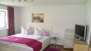 A bedroom with a bed, a television, a small table, and a painting on the wall. - Holiday apartment in Grän with swimming pool (Grän)