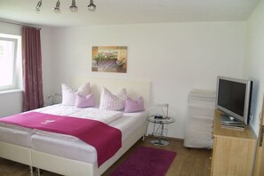 A bedroom with a bed, a television, a small table, and a painting on the wall. - Holiday apartment in Grän with swimming pool (Grän)