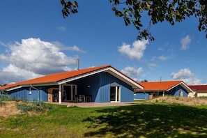 A blue building with a red roof, a covered outdoor area, and a grassy foreground.