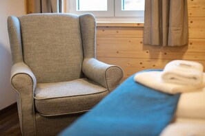 A room with a single armchair and a bed with a blue blanket.
