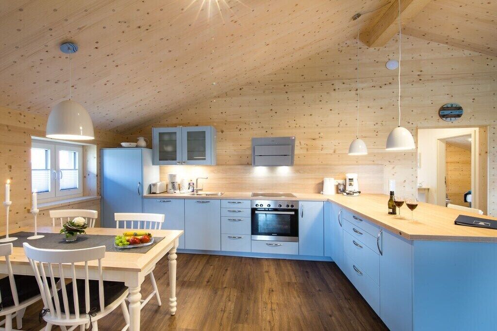 A modern kitchen with wooden walls, a central island, and pendant lighting.