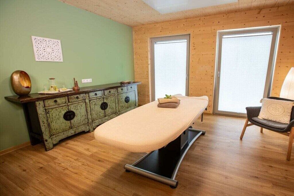 Une pièce comprenant une table de massage, un meuble en bois et une chaise.