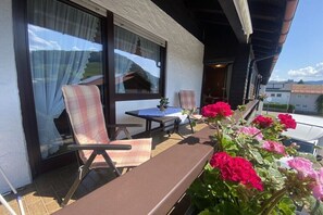 Ein Balkon mit Tisch, Stühlen und einem Blumentopf.