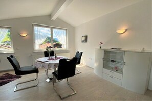 A dining area with a round table, four chairs, and a cabinet with glass doors. - Holiday apartment with 2 bedrooms (Oberstaufen)