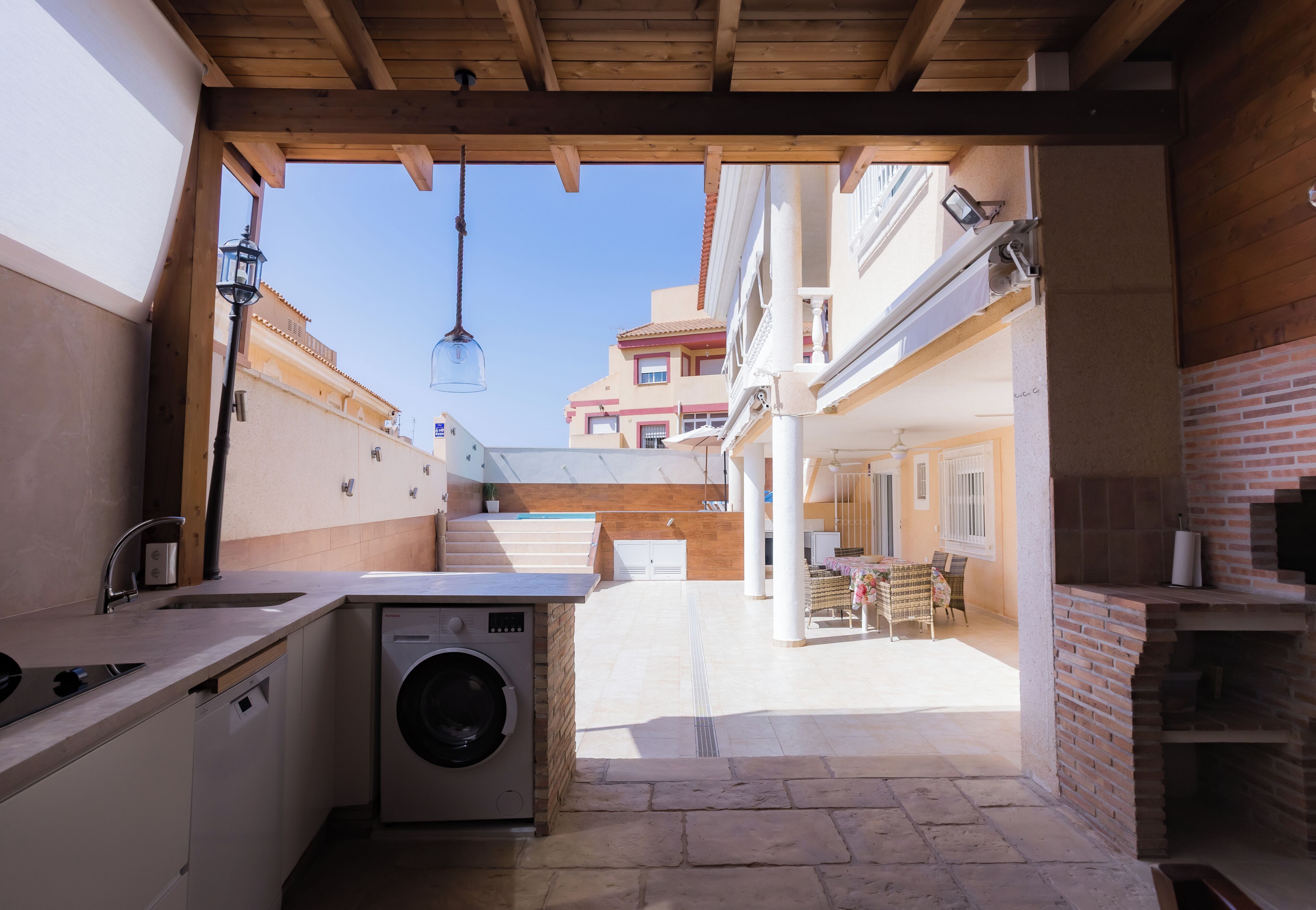 A laundry area with a washing machine, a sink, and a hanging light fixture.