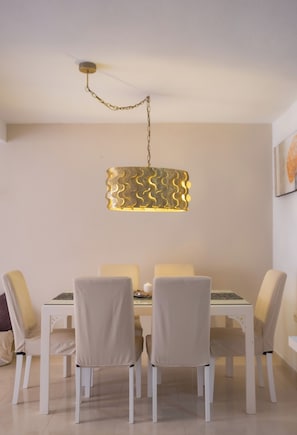 A dining area with a table and chairs, a pendant light fixture, and a wall-mounted painting.