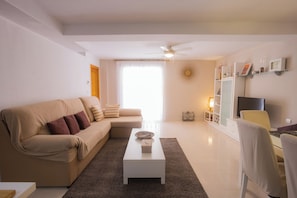 A living room with a sofa, a coffee table, a TV, and a ceiling fan.