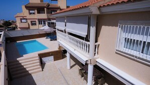 Ein Wohngebäude mit Schwimmbad, Sitzgelegenheiten im Freien und einer überdachten Terrasse.