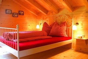 Ein Schlafzimmer einer Holzhütte mit Bett, weißer Geländer und zwei Wandlampen.