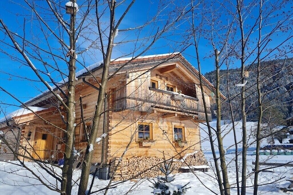 Eine Holzhütte mit Balkon, umgeben von schneebedeckten Bäumen.