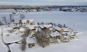 Een besneeuwd dorpje met traditionele houten huizen, een heldere lucht en een bevroren meer op de achtergrond.