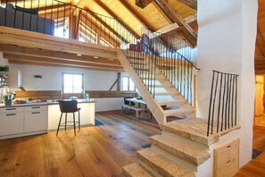 Ein geräumiges Loft mit einer Holztreppe und einer Küchenzeile.