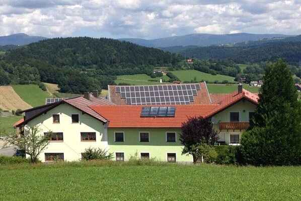 Un edificio a due piani con tetto in tegole rosse e pannelli solari al piano superiore.