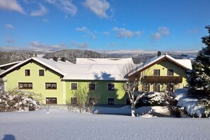 Un edificio a due piani con tetto innevato e cielo sereno.