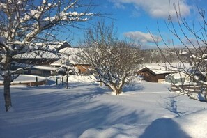 Eine verschneite Landschaft mit Gebäuden und kahlen Bäumen.