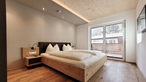 Ein modernes Schlafzimmer mit einem hölzernen Bett, einem Nachttisch und einem großen Fenster.