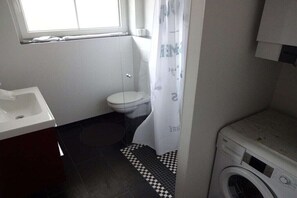 A compact bathroom with a toilet, sink, and washing machine. - Holiday apartment in Sarkwitz with parking (Sarkwitz)
