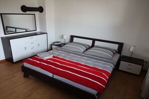 A bedroom with a bed, a bedside table, a nightstand, a dresser, and a mirror. - Holiday apartment in Sarkwitz with parking (Sarkwitz)