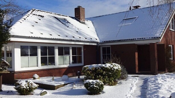Una casa a due piani con tetto imbiancato dalla neve e facciata in mattoni.