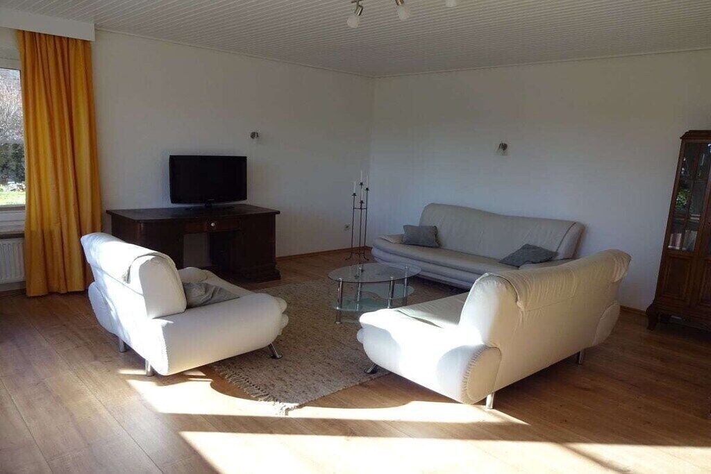 Una sala de estar con un sofá, sillones, una mesa de centro, un televisor y un mueble de almacenamiento.
