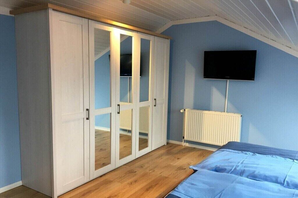 A bedroom with a bed, a wardrobe, a television, and a radiator.
