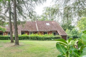 A building with a tiled roof, surrounded by trees and a grassy area. - Holiday Village 39 B (Boltenhagen)