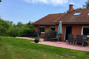 A residential house with a brick exterior, a tiled roof, and a patio area with outdoor furniture. - Holiday Village 39 B (Boltenhagen)