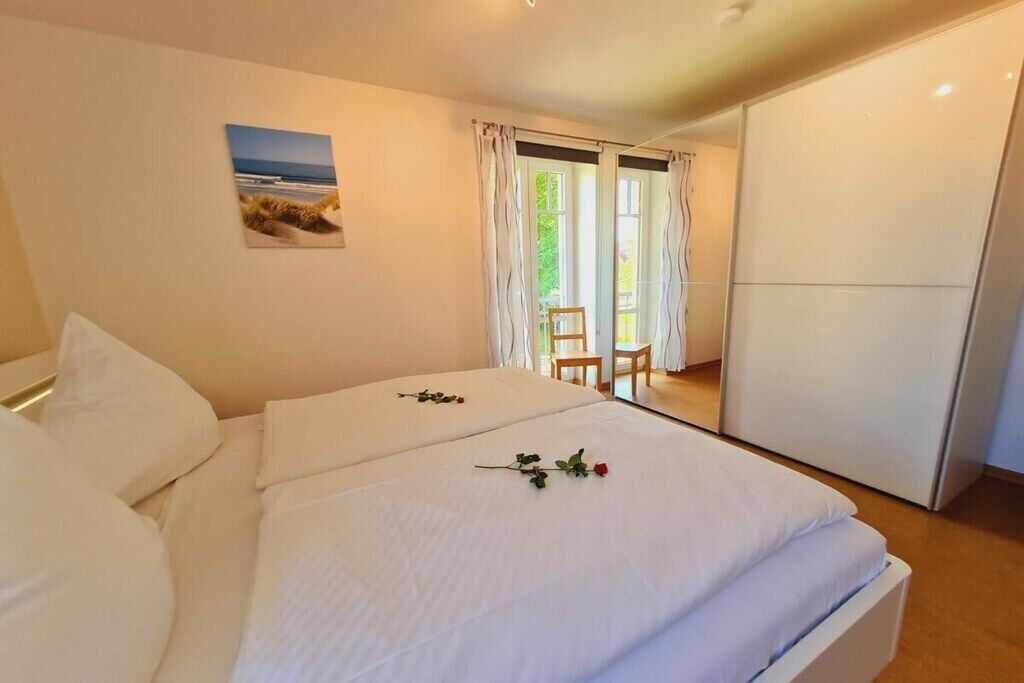 A hotel room with two beds, a view of the outdoors through a window, and a painting on the wall.