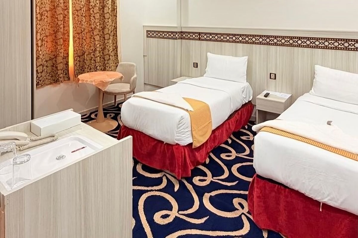 Habitación de hotel con dos camas, un escritorio, una silla y baño.