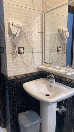 A bathroom with a white sink, a mirror, and two hair dryers mounted on the wall. - Outad United Hotel 2 (Makkah)