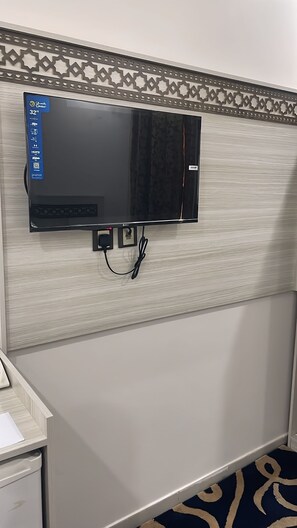 A flat-screen TV mounted on a wall with a decorative border, a power outlet, and a cable connected to it. - Outad United Hotel 2 (Makkah)
