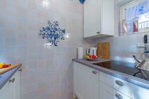 Een keuken met witte kasten, een aanrecht en een decoratieve blauwe tegel.