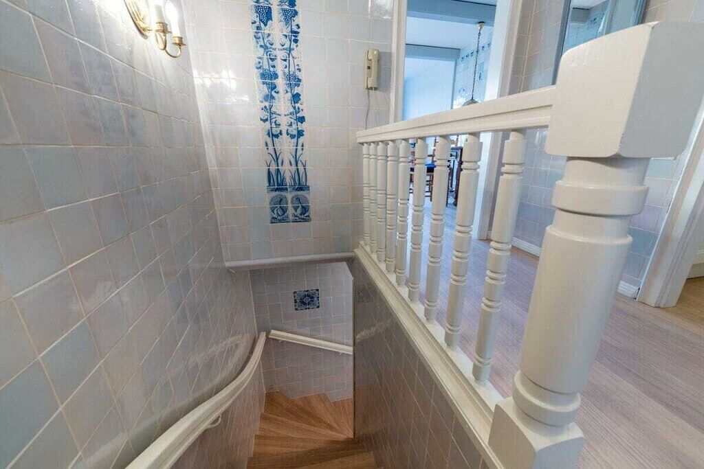 Eine Treppe mit weißen Balustraden und einer blauen Wand mit dekorativen Fliesen.