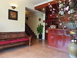 A reception area with a wooden bench, a reception desk, a potted plant, and a staircase leading to another room. - Sapa Casa Bella Homestay (Sa Pa)