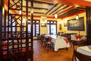 An indoor dining area with tables and chairs, a wooden partition, and a large framed picture on the wall. - Sapa Casa Bella Homestay (Sa Pa)