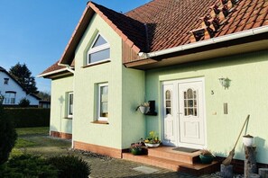 A two-story house with a green exterior, a brown roof, and a white front door. - Holiday apartment in Walow with swimming pool (Walow)