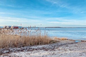 A coastal area with a sandy beach, a body of water, and a small building with a flag. - Holiday apartment in Walow with swimming pool (Walow)