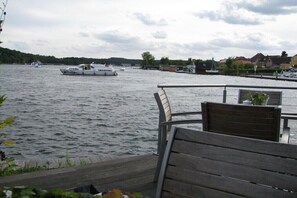 A waterfront view with a dock, wooden benches, and a boat on the water. - Holiday apartment in Walow with swimming pool (Walow)