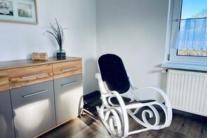 A room with a wooden cabinet, a white chair, a window with a view, and a radiator. - Holiday apartment in Walow with swimming pool (Walow)