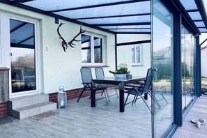 A conservatory with a glass roof, a dining table with chairs, and a decorative antler on the wall. - Holiday apartment in Walow with swimming pool (Walow)