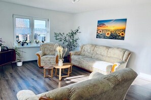 A living room with a sofa, chairs, a coffee table, and a window with plants. - Holiday apartment in Walow with swimming pool (Walow)