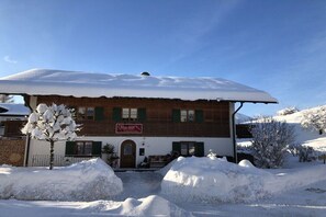 Un edificio de dos pisos con tejado cubierto de nieve y un letrero que indica que es un restaurante.