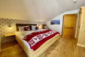 Ein Schlafzimmer mit einem Bett, einem Nachttisch, einer Wandleuchte, einer Holztür und einem kleinen Stuhl.