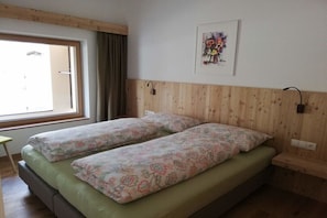 A room with two beds, a window, a wooden headboard, and a wall-mounted light fixture. - At Niedermoar- "Brenngass" (Naturns)