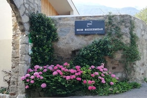Un muro de piedra con un letrero que dice 'BEIM NIEDERMOR' y un grupo de flores rosas.